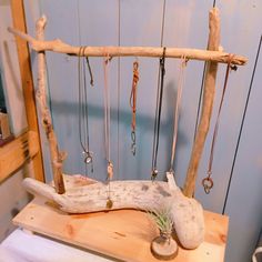 a piece of driftwood with various necklaces hanging from it's sides on a table