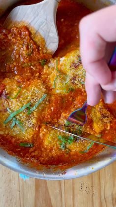 someone using a spoon to scoop some food out of a bowl on a wooden table