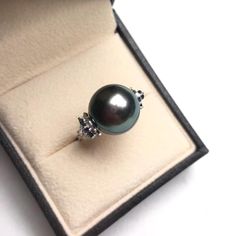 This is a stylish and beautiful ring earring. Product Information Origin Tahitian Pearl Jewelry Processed in Japan Material Tahitian Pearl and 18K White Gold Dimensions Custom Pearl Shaped: Round Size: 14-15mm Black Tahitian Pearl Quality: AAAA Nacre: Very Thick Color: Black with Peacock Green Luster Luster: Very High Accessories Metal: 18K White Gold Other: 0.60ct of SI Quality Natural Diamond and 1.80ct of Sapphire Round Tahitian Pearl Gemstone Jewelry, Tahitian Pearl Gemstone Jewelry, Luxury Tahitian Pearl Jewelry For Anniversary, Luxury Tahitian Pearl Anniversary Jewelry, Elegant Ring-shaped Earrings For Formal Occasions, White Gold Tahitian Pearl Jewelry With High Luster, Elegant Aaa Quality Sterling Silver Rings, Round Tahitian Pearl Jewelry With High Luster, Tahitian Pearl Ring Jewelry As Gift