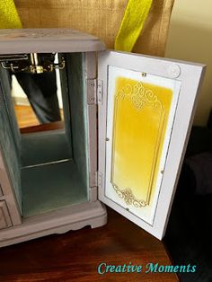 an open dollhouse with a yellow door and some drawers on the table next to it