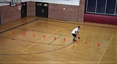 a man standing on top of a basketball court with a ball in his hand and orange cones around him