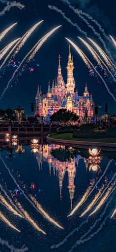 fireworks are lit up in the sky above a castle at night with reflection on water