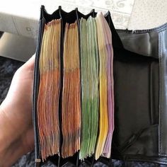 a person is holding a wallet full of different colored papers in their left hand,