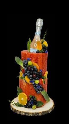 a watermelon cake with fruit and wine on top is displayed in front of a black background