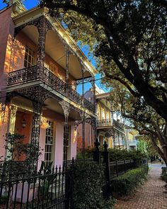 an old house with wrought iron railings and trees