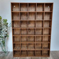 a wooden bookcase with many compartments on the front and bottom, next to a vase filled with flowers