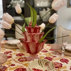 there is a vase with flowers in it on the dining room table set for dinner