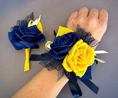 two wrist corsages with blue, yellow and black flowers on each one hand