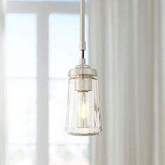 a light fixture hanging from a ceiling in front of a window with white drapes