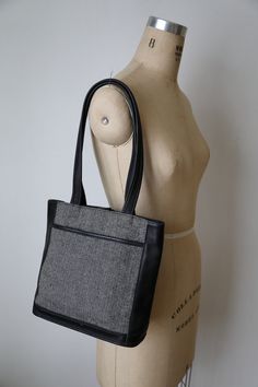 Coach leather and wool tote handbag-- Classically styled handbag is the perfect addition for the professional woman. The exterior is black and gray wool tweed in a herringbone pattern with black leather trim and accents. There is a slip pocket on the front. The interior has a leather tab and snap closure and is lined in a brown plaid fabric. Zipper pocket inside. Dual leather handles can be worn on the shoulder or carried by your side. Serial number: H9D-6127 Made in the United States Measuremen Wool Tote, Leather Satchel Handbags, Plaid Fabric, Brown Plaid, Tote Handbag, Coach Leather, Satchel Handbags, Herringbone Pattern, Leather Handles