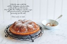 a cake sitting on top of a wire rack next to a bowl of powdered sugar