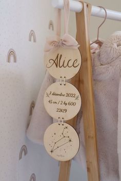 three personalized wooden signs hanging on a clothes rack in a nursery room with a teddy bear