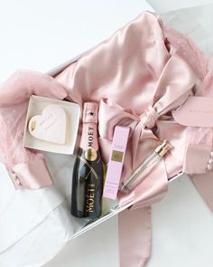 the contents of a pink gift box are laid out on a white tablecloth,