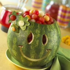 a watermelon carved to look like a face with fruit in it's mouth