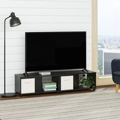 a living room with a couch, chair and television on the stand in front of a window