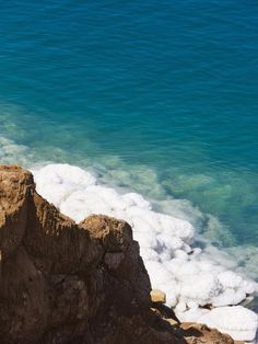 a man standing on top of a cliff next to the ocean