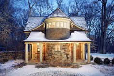 a stone house with snow on the ground and trees in the backgrouds