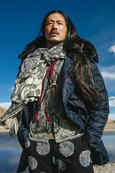 a man with long hair standing next to water