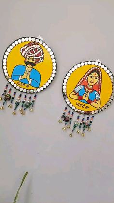 two decorative wall hangings decorated with colorful paintings and beads on the side of a wall