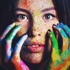 a woman with her hands on her face covered in paint