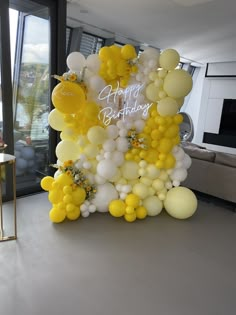 a birthday cake made out of yellow and white balloons