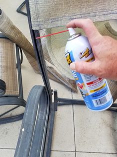 a hand is spraying something on the floor next to a chair and other furniture items