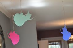 three different colored paper cutouts hanging from strings