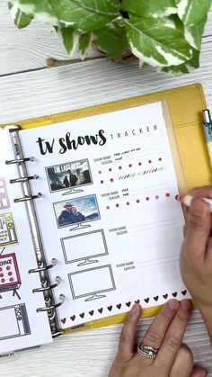 someone is doing their own planner on a desk with a potted plant in the background