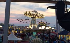 an amusement park filled with lots of rides and people flying around at dusk or dawn