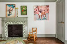 a living room filled with furniture and paintings on the wall above a fire place in front of a fireplace