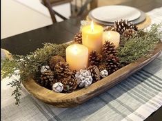 a wooden tray with pine cones and candles