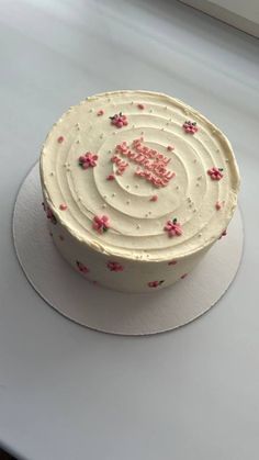 a cake with white frosting and pink sprinkles sitting on top of a table