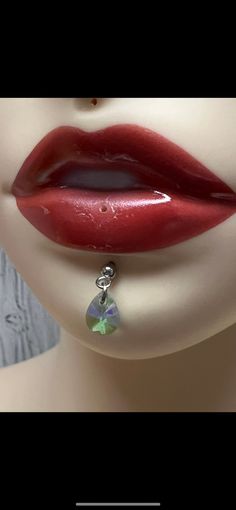 a woman's lips with red lipstick and green earrings