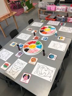 the table is covered with paper plates and drawings for children's art projects on it