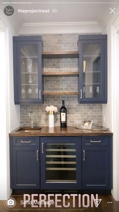 a kitchen with blue cabinets and white tile backsplashing, wine bottle on the counter