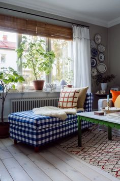 a living room filled with furniture next to a window covered in white curtains and pillows