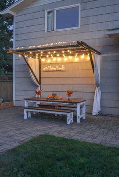 an outdoor patio with lights strung over the table and bench under the pergolated roof