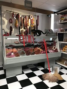 a display case filled with lots of donuts and sausages on top of black and white checkered flooring