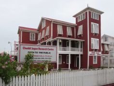 a red building with white balconies on the front and second story is next to a picket fence