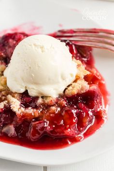 a white plate topped with fruit cobbler and ice cream on top of red sauce