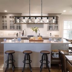 three stools sit at the center of a kitchen island with two bar stools