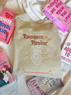 several books and t - shirt laying on top of a white bed with the words romance reader