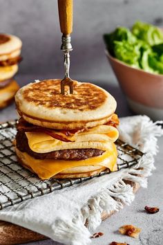 a stack of pancakes sitting on top of a cooling rack next to a bowl of lettuce