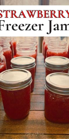 several jars filled with strawberry freezer jam on top of a wooden table next to a sign that says, strawberry freezer jam