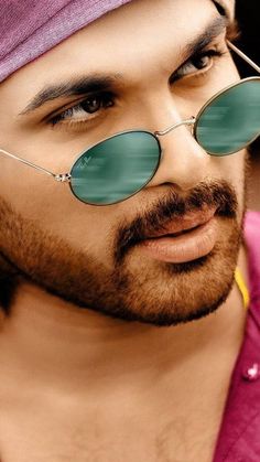 a close up of a person wearing sunglasses and a pink shirt with a bandana