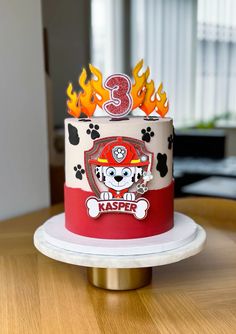 a birthday cake with fire and paw prints on the top is sitting on a table