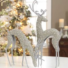 two silver reindeer figurines sitting on top of a table