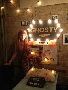 a woman standing next to a table with a cake on it and lit candles in front of her