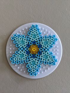 a white plate with blue and yellow designs on the top is sitting on a wall