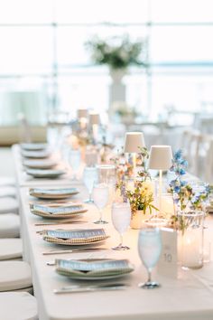 a long table set with place settings and flowers on the tables for an elegant dinner